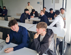Schüler:innen sitzen in Gruppen an Arbeitstischen
